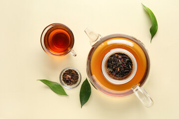 Stylish tea pot, cup of tea and green leaves on beige background