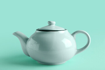 Stylish tea pot on turquoise background, closeup