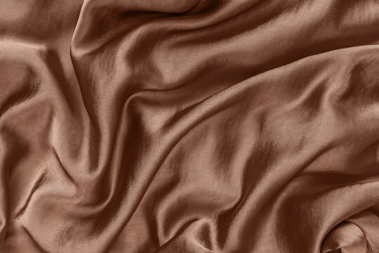 Elegant smooth brown satin fabric with rich texture and flowing drapes in color of the year 2025 mocha mousse