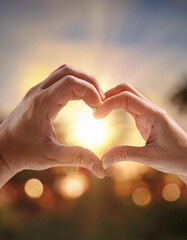 Two hands forming a heart shape, symbolizing love and unity against a warm sunset backdrop