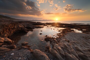 Sunset over rocky coastline with tranquil water pools reflecting vivid colors