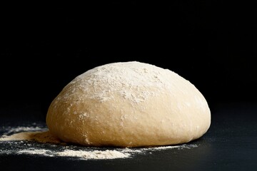 Freshly kneaded dough resting on a black surface ready for baking in a cozy kitchen environment