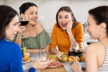 Happy women congregated around a festive table; participating in animated discussions and enjoying the delights of red wine