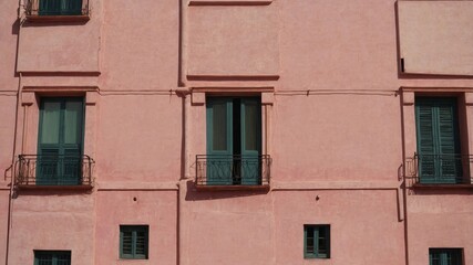 Obraz premium Pink plaster facade with small urban windows