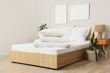 White pillows with folded blanket on bed in light room interior