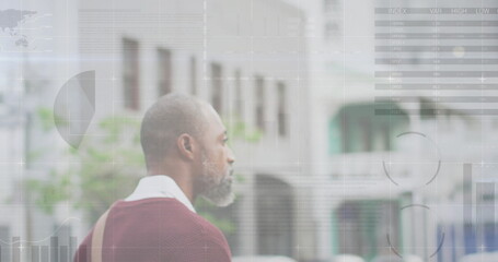 Image of diagrams and data processing over african american man walking in city