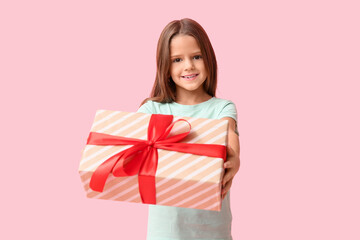 Happy little girl with gift box on pink background