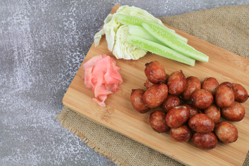 Thai northeastern sausage (Sai Krok Isan) made from fermented pork and rice eat with cabbage, cucumber and pink ginger. Street food market