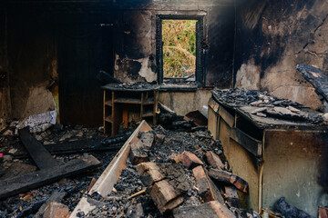 Fire aftermath. Burnt wooden house interior with remnant of furniture