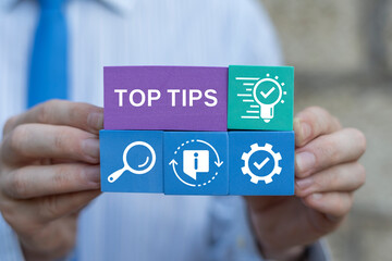 Business man holding colorful blocks sees inscription: TOP TIPS. Top tips business education...
