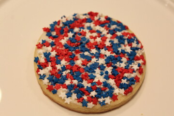 A patriotic-themed cookie decorated with red, white, and blue sprinkles.
