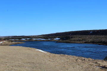 A winding river in Iceland surrounded by grassy plains.