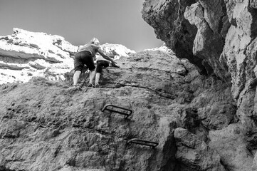 A man is climbing a rock wall with a woman following him