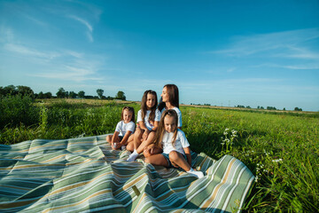 A mother and her children are playing and hugging in a field of flowers.
