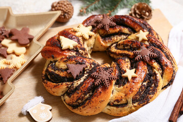 Wooden board with tasty Christmas pastry wreath and cookies, closeup
