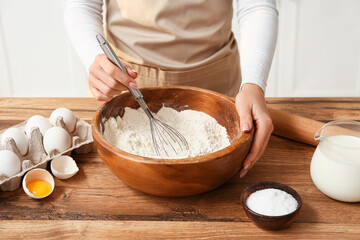 Woman preparing dough with ingredients on kitchen counter