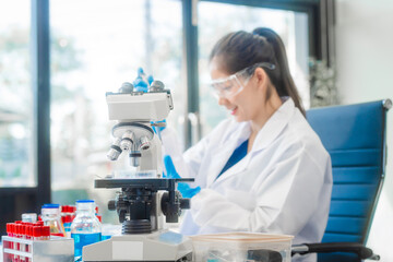 A young Asian woman works in a laboratory, conducting chemical and blood tests. Wearing goggles, research and analysis, combining science and technology in a professional and medical environment.