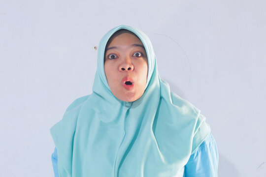 Portrait of a Muslim adult woman standing with a shocked and surprised face, portrayed against a white background.