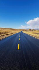Naklejka premium A long, empty road stretches through a vast, open landscape under blue skies.