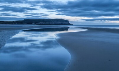 Fototapeta premium Tranquil coastal scene during twilight with reflective water.