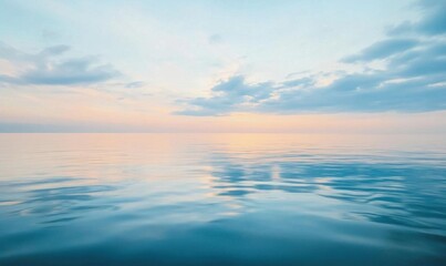 Fototapeta premium Calm ocean waters reflecting a serene sky at sunset.
