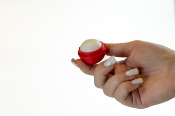 A hand offering a lip moisturizing balm on a white background.