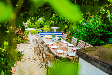Inviting Outdoor Dining Space With Wooden Table Set for Celebration Surrounded by Lush Greenery and Bright Foliage Creating a Peaceful Garden Ambiance for Enjoyable Gatherings With Family and Friends