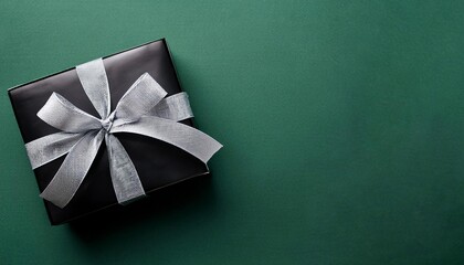 Black Gift Box with Silver Ribbon on Dark Green Background. Top View of Brotherhood Day Gifts with Copy Space