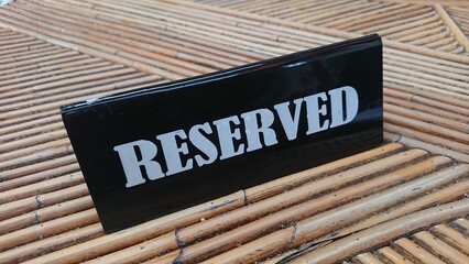 Reserved Sign, black acrylic at bamboo table white text