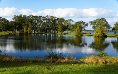 A peaceful park setting with a calm pond reflecting the surrounding trees and sky near Lake Hartridge Nature Park, Winter Haven, Florida, U.S