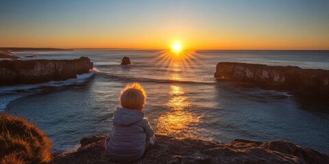 Fototapeta premium The sun dipping below the horizon with its light reflecting beautifully off the ocean surface, seen from a high cliff, surrounded by rocky outcrops. 