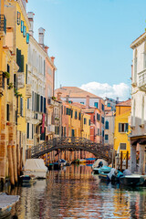 colorful homes of Venice Italy with canal and old metal pedestrian bridge stretching across 