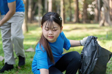 Young Asian girl volunteering in park collecting litter