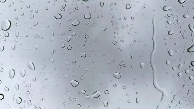 Raindrops flowing down the window glass with a dark cloud background