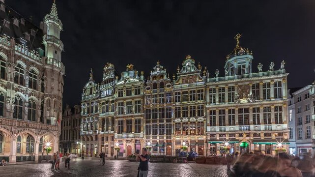 Night hyperlapse of the illuminated Grand Place Guilds facade in Brussels, Belgium. Historic art guild associations in Baroque architecture timelapse, with people walking on the UNESCO-listed square
