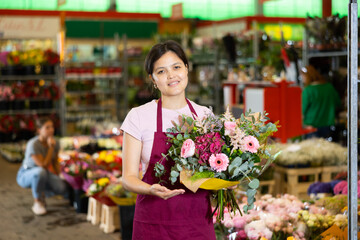 Portrait of positive female flower market seller with bouquets of flowers