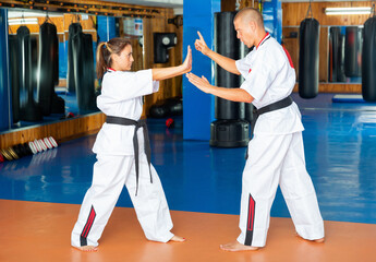 Trainer teaching Latin woman kata during karate training. © JackF