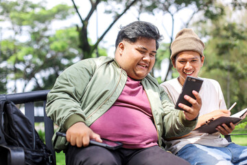 Smiling Young Fat Man College Student Showing Funny Video on Smartphone To His Friend