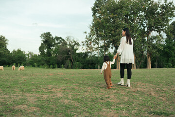happy mother walking with her toddler baby girl on grass field