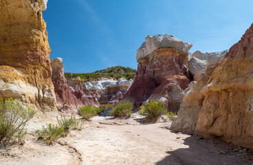 Fototapeta premium Breathtaking view of colorful rock formations under a clear blue sky in a serene canyon at midday, showcasing natural beauty and geological diversity in a remote area