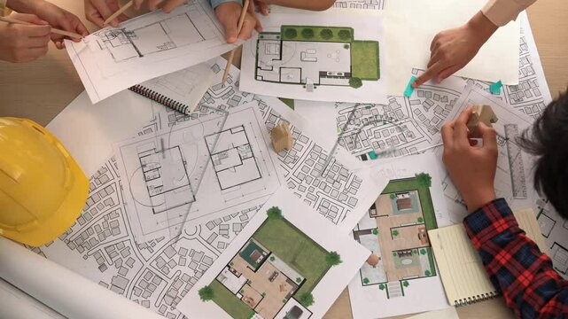 Architect and safety engineer discussion about building construction use blueprint on table with architectural document, measurement tool and wooden block scatter around at modern office. Delineation.