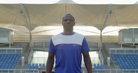 Front view of an African American male field hockey player, wearing a blue team strip, walking towar