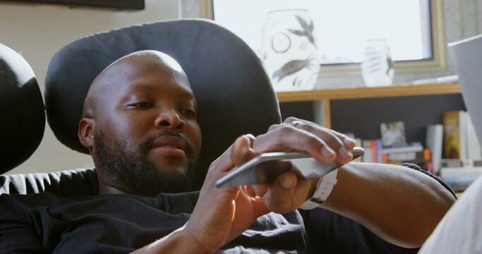 Side view of African american man using smartwatch in a comfortable home - Powered by Adobe
