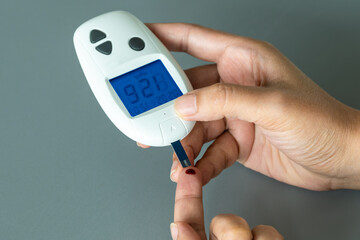 woman's hands checking diabetes and hyperglycemia with digital blood sugar meter. Healthcare and medical concept	
