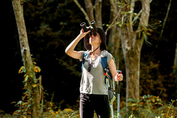 Hikers or explorers on journey carrying backpack, trekking poles and holding binoculars looks into the distance observing and possibly guide trekking and trail exploration holiday ecotourism concept.