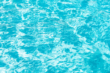 Water background. Blue water, ripples and highlights. Texture of water surface and tiled bottom.