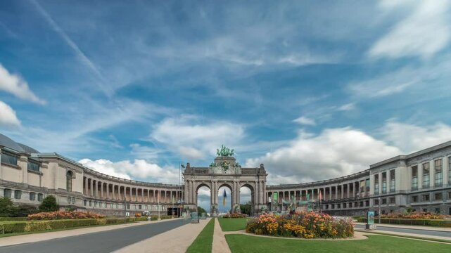 Hyperlapse of the Cinquantenaire Arcade in Jubelpark with flowerbed, Brussels, Belgium. The memorial triumphal arch stands tall under clouds timelapse, symbolizing Belgian history and independence.