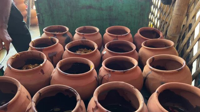 A man putting onion and spices in earthen pot to make Champaran Handi Mutton