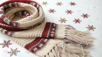 A cozy knit scarf lies on a snowy ground in a winter forest, inviting viewers to embrace the warmth and beauty of the season