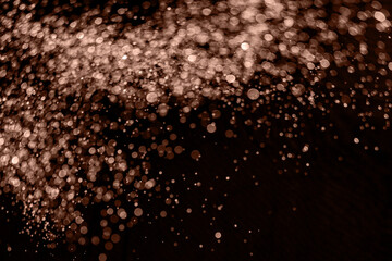 Blurry garland lights on a dark background. Festive Christmas and New Year background. Soft focus. Image toned in color of 2025 year - Mocha Mousse